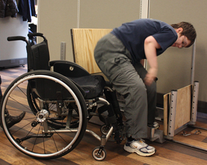 This image shows a research subject transferring to a custom-built transfer station set at a lower height than her wheelchair seat.  Please see body of the text in the final report for more description about the study.